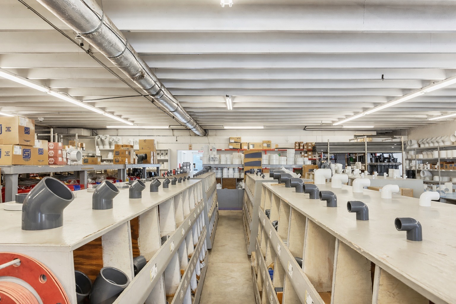 Industrial warehouse with PVC pipe fittings on shelves.