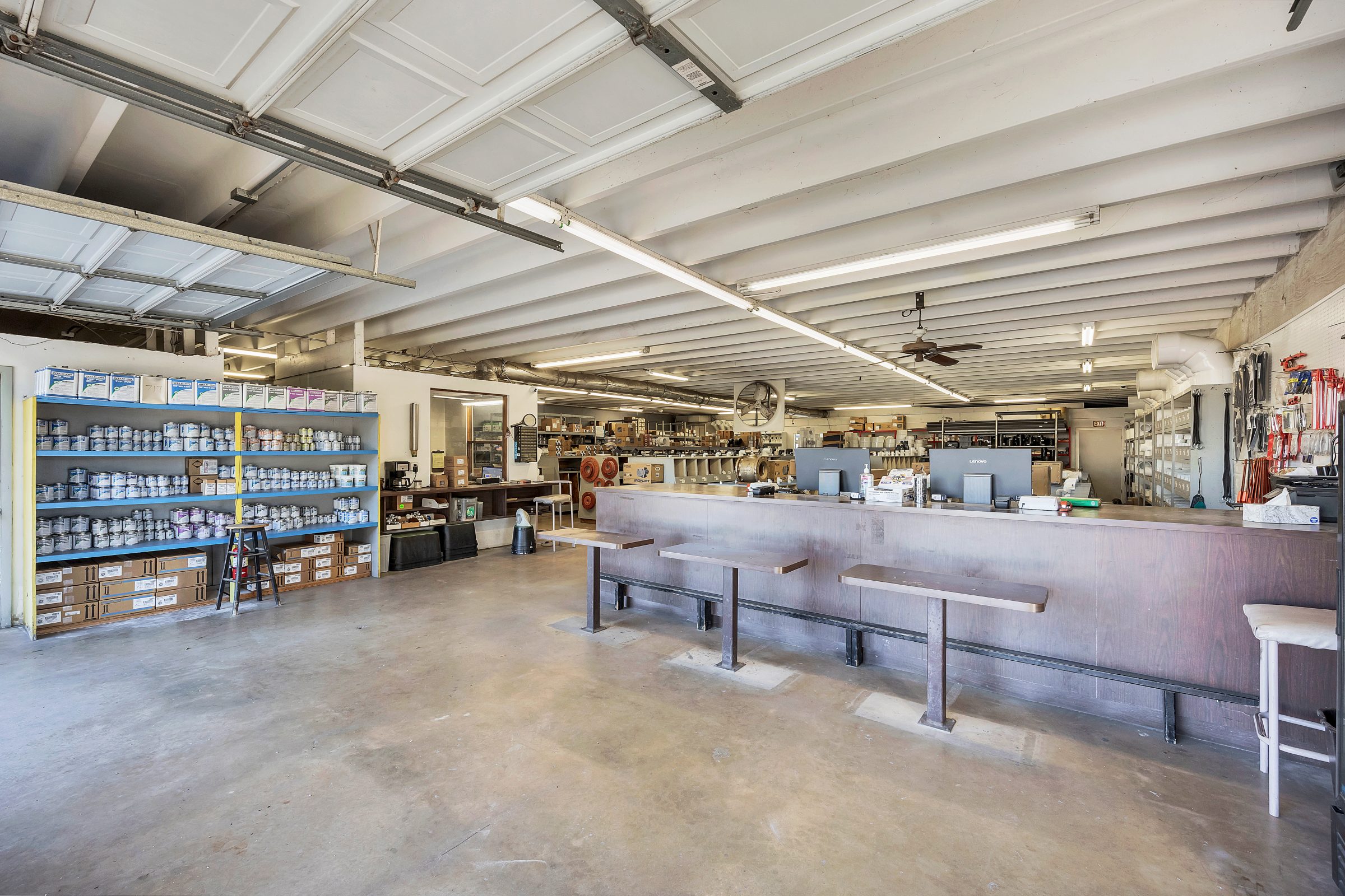 Spacious warehouse interior with shelves and desks.