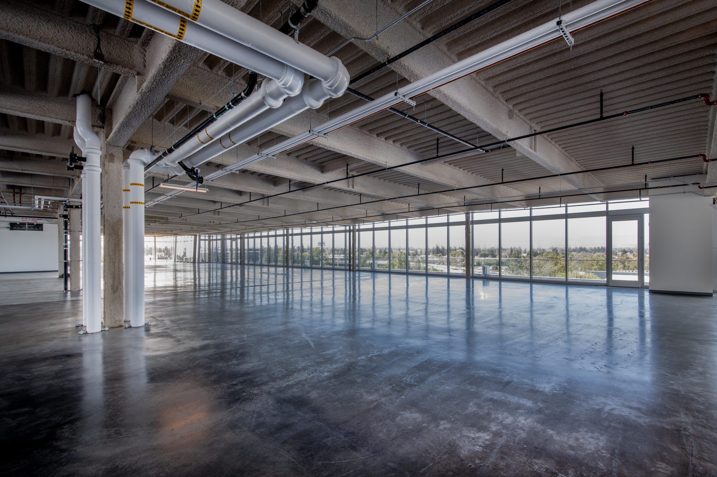 Spacious, empty industrial loft with large windows.
