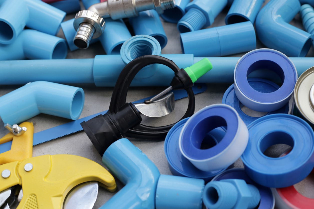 Assorted plumbing tools and blue pipes collection.