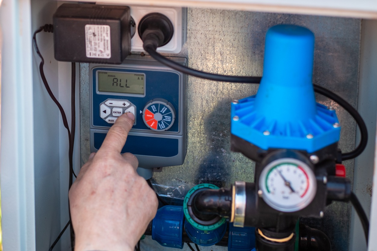 Hand pressing button on irrigation system controller.